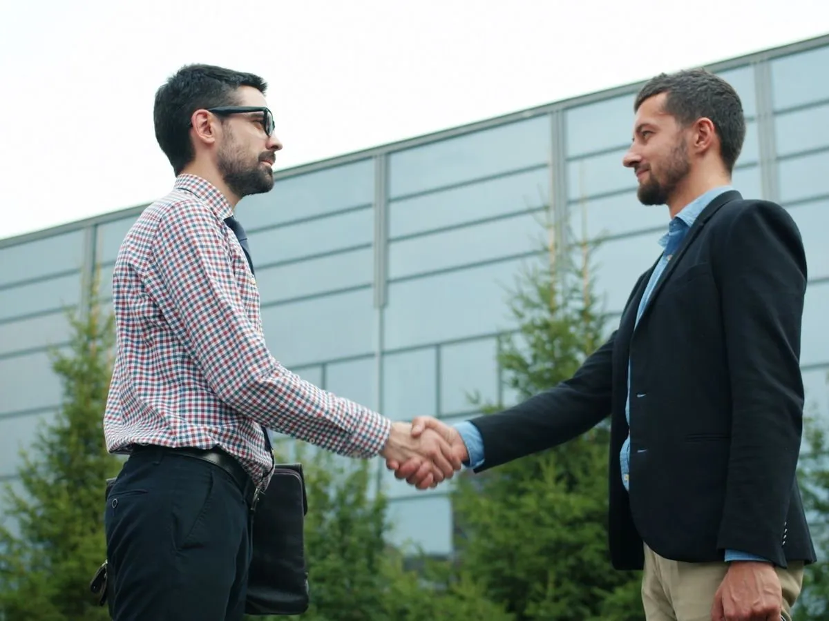Two business partners shaking hands outside an office