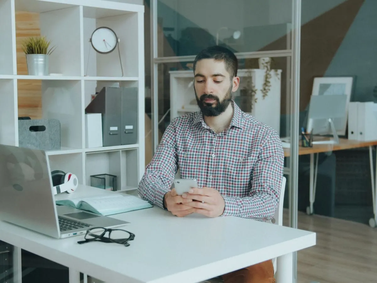 Man checking his phone at an office desk