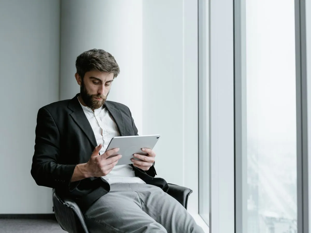 Professional reading on a tablet by an office window