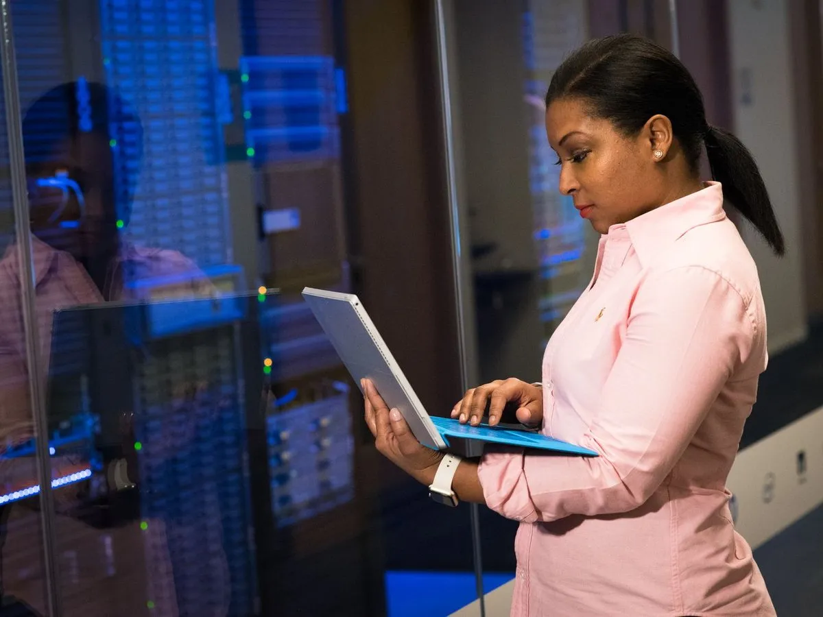 An IT engineer working on a laptop in a server room